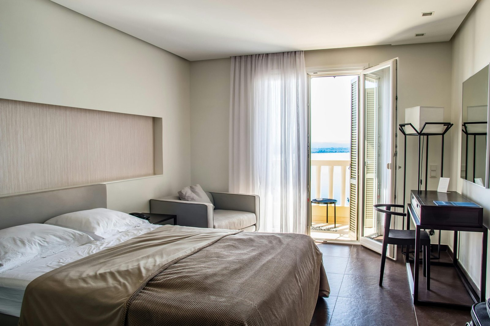 Spacious, elegantly furnished hotel room featuring a balcony with a sea view and modern amenities.